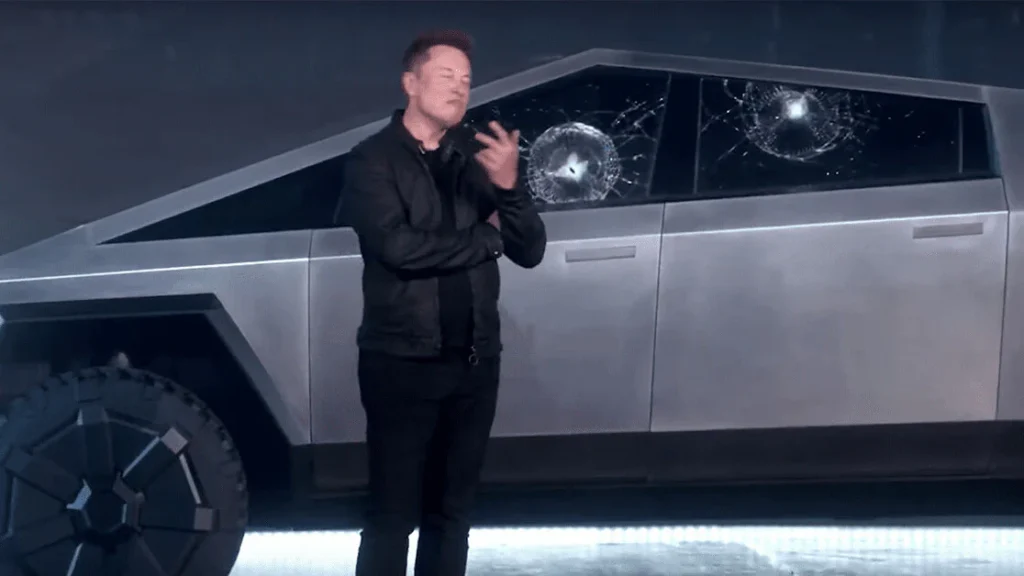Elon Musk stands infront of the Cybertruck with broken windows