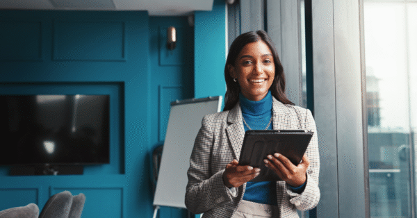 Smiling product manager holding a tablet in a modern office, ready to present a good product strategy to her team.